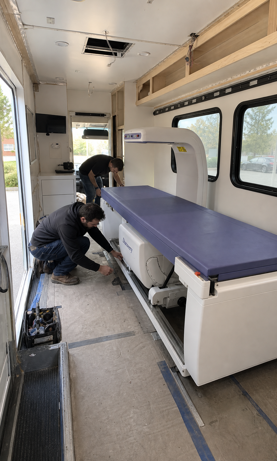 Technicians fitting a Hologic Discovery-style DEXA scanner inside the first VitalScan mobile unit